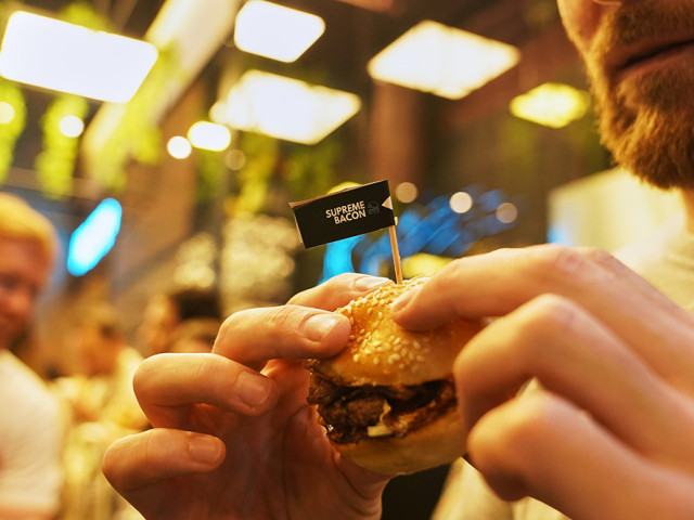 Gost u rukama drži SMASH burger u restoranu SMASHER&CO